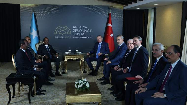 Toplantı salonunda iki sıra halinde oturan kişiler; arkalarında Türk ve Somali bayrakları ile Antalya Diplomasi Forumu yazısı görülüyor.