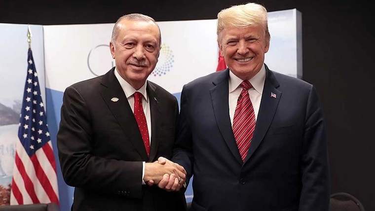 El sıkışan iki adam, biri kravatlı ve takım elbise giymekte, diğeri ise ceket ve kravatla görünmekte.