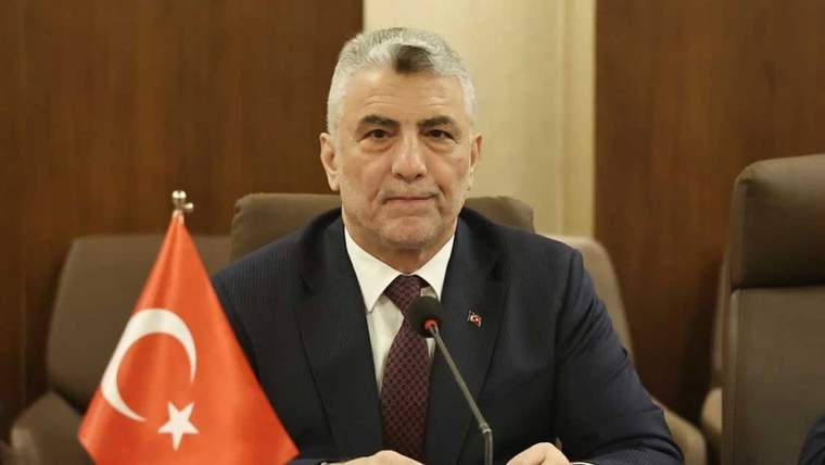 Türk bayrağının önünde oturan bir kişi, toplantı salonunda görüntüleniyor.