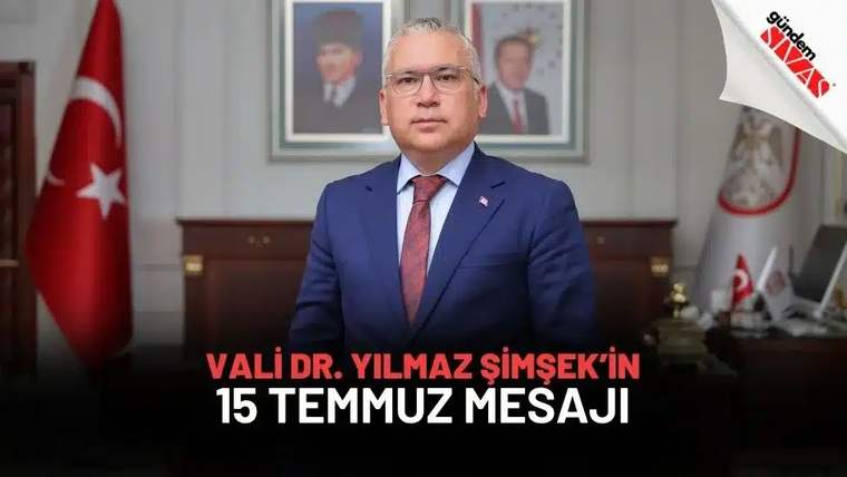 Kırmızı kravat takan bir kişi, arkasında Türk bayrağı ve portreler ile birlikte duruyor.