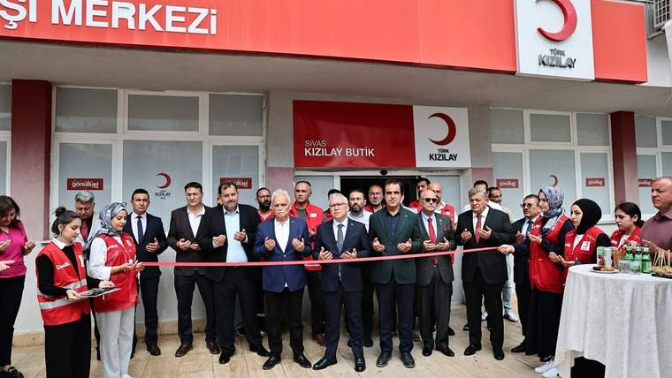 Kızılay Butik tabelası önünde, ellerinde kurdele tutan kalabalık ve kesim için bekleyen makaslar görülüyor.