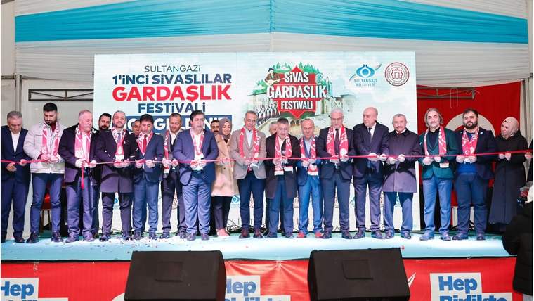 Sahnede kurdele tutan kalabalık bir grup, arkasındaki Sultangazi ve Sivaslılar yazılı pankartın önünde duruyor.