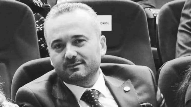 Koltukta oturan bir kişi, takım elbise giymiş ve kravat takmış.