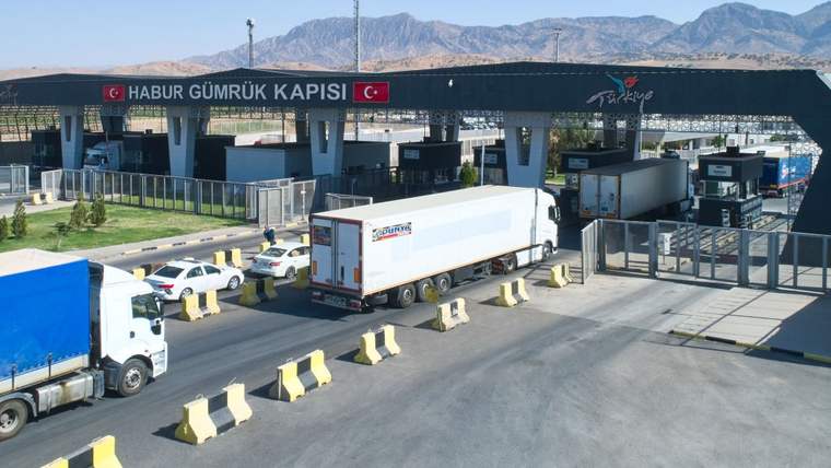 Habur Gümrük Kapısı tabelası önünde, kontrol noktaları ve bariyerler arasında bekleyen yük kamyonları görülüyor.