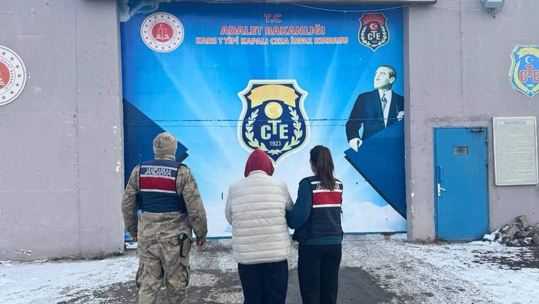 Üzerinde üniforma olan iki kişi, kapalı ceza infaz kurumunun önünde duruyor.