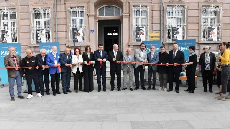 Kurdele kesen kalabalık, arka planda tarihi bir bina yer alıyor.