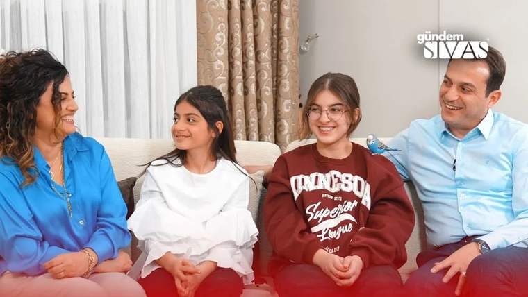 Bir odada koltukta yan yana oturan dört kişi, birbirlerine bakarak gülümsüyor.