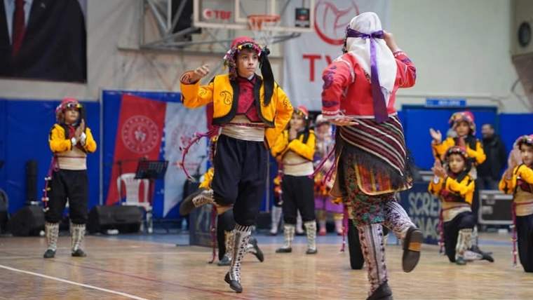 Spor salonunda geleneksel kıyafetler giyen çocuklar, halk oyunu gösterisi sırasında dans ediyor.