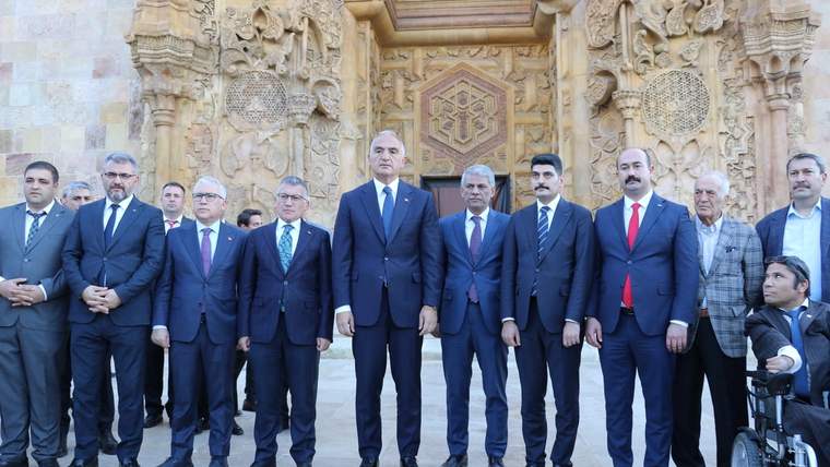 Divriği Ulu Cami önünde, bakan ve yanındaki kişiler poz veriyor.