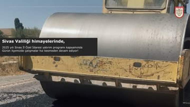 Yolda asfaltlama yapan bir iş makinesi, güneşli bir günde çalışıyor.