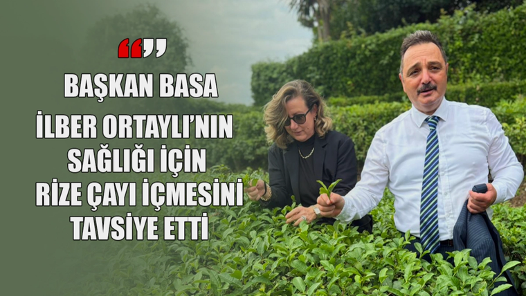Bıyıklı bir erkek ve güneş gözlüklü bir kadın, yeşil çay bitkileri arasında ellerinde dallarla duruyor.