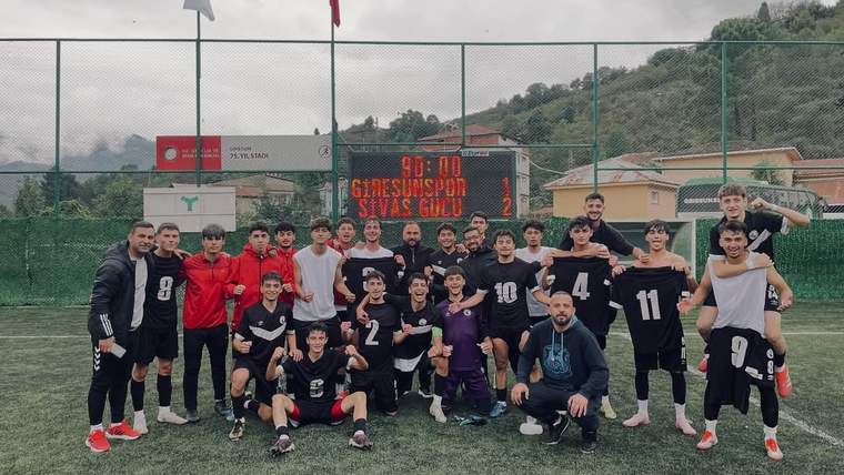 Futbol sahasında forma giyen oyuncular, skor tabelasının önünde takım halinde poz veriyor.