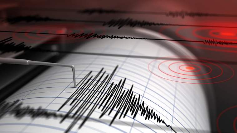 Kâğıt üzerindeki siyah sismograf çizgileri ve kırmızı eş merkez dalgalarını gösteren deprem grafiği