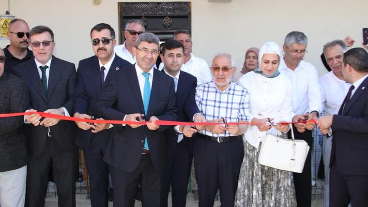 Köy konağının açılışında kurdele kesen kalabalık bir grup insan.