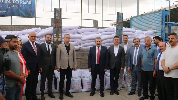 Bir grup insan, arka planda beyaz tohum torbalarının önünde poz veriyor.