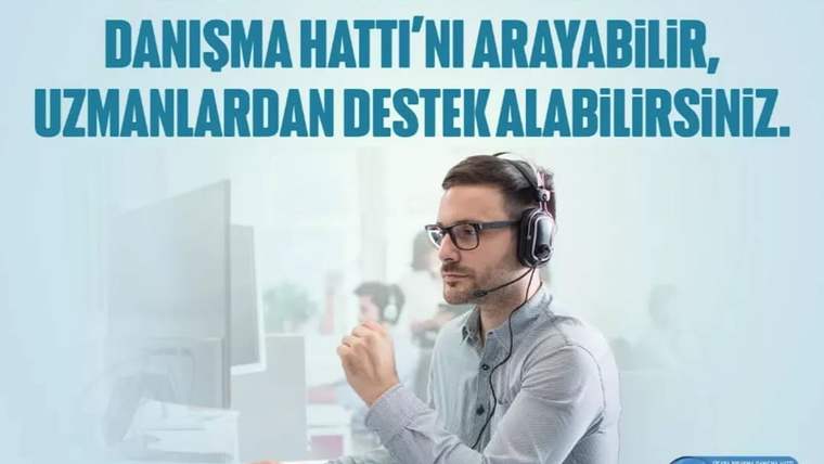Kulaklık takan bir kişi, bilgisayar ekranına bakarak telefonla konuşuyor.