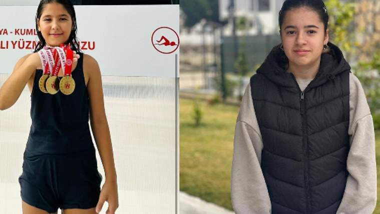 Yüzme madalyalarını tutan bir kız çocuğu, yanında başka bir kız çocuğu ile birlikte duruyor.