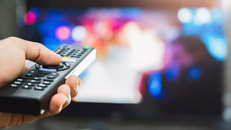 Bir el, televizyon kumandasını tutarak ekrana odaklanmış.