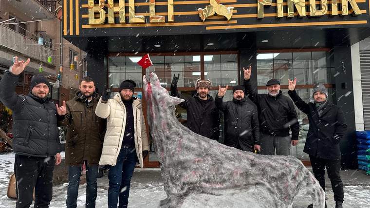 Üzerinde “BALIK FINDIK” yazan iş yerinin önünde, kardan yapılmış bozkurt heykeli ve çevresindeki kişiler görülüyor.