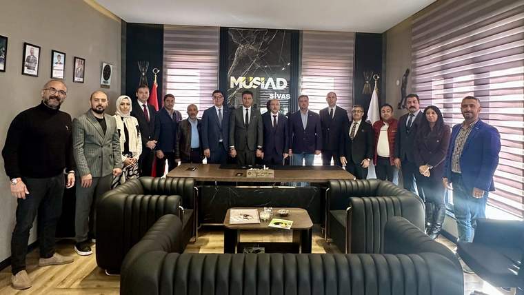 Duvarında “MÜSİAD Sivas” yazısı bulunan ofiste, bir masa çevresinde yaklaşık 20 kişi birlikte duruyor.
