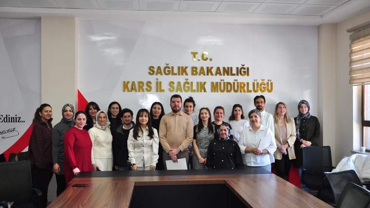 Kars İl Sağlık Müdürlüğü'nde bir grup insan, eğitim sonrası fotoğraf çekiliyor.