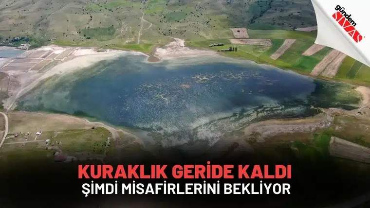 Yeşil tepeler ve tarlalarla çevrili, kıyıları kısmen kurumuş bir göletin havadan görünümü.