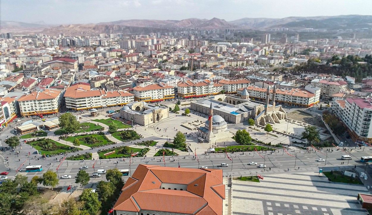 Sivas'ın merkezine ait bir hava görüntüsü, çeşitli binalar ve yeşil alanlar görünmekte.
