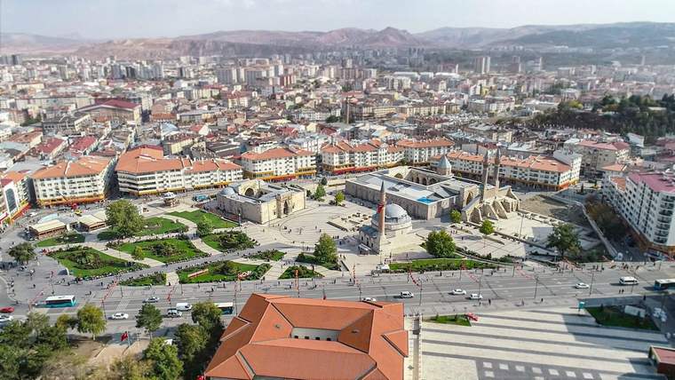 Sivas'ın merkezine ait bir hava görüntüsü, çeşitli binalar ve yeşil alanlar görünmekte.