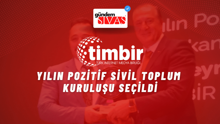 Bir kişi, ödülünü alırken gülümseyerek poz veriyor.