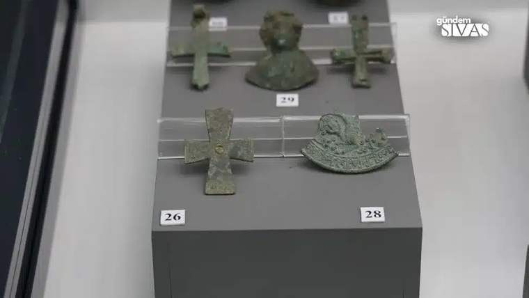 Müze vitrininde sergilenen çeşitli bronz nesneler, arasında haç ve mühürler bulunuyor.