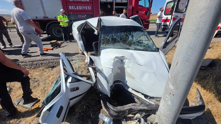 Direğe çarpmış ağır hasarlı otomobilin çevresinde itfaiye aracı ve görevliler görülüyor.