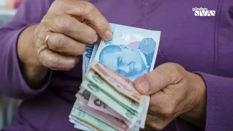 Yaşlı bir kişinin elinde çeşitli banknotlar, paraların üstünde Atatürk resmi var.