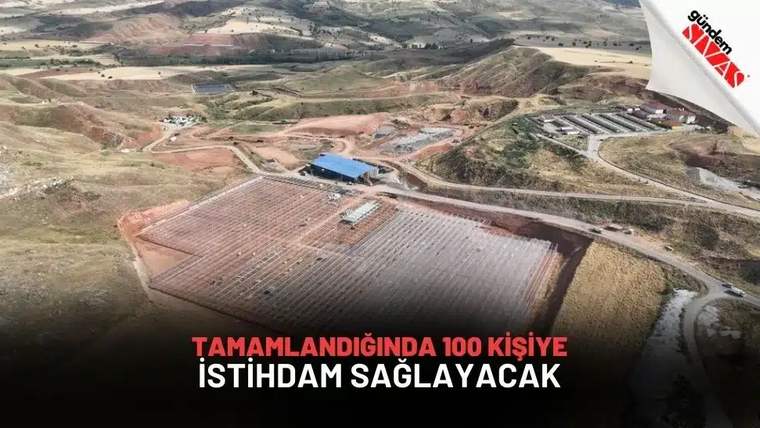 Havadan çekimde, tepeler arasındaki geniş arazide paralel sıralar, yollar ve mavi çatılı yapılar görülüyor.