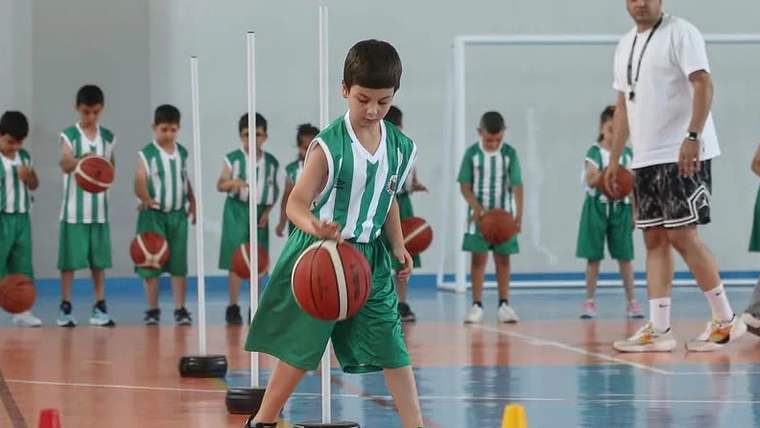 Basketbol topu ile oynayan çocuk, spor salonunda antrenman yapıyor.