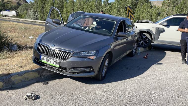 Yol kenarında gri otomobil ile beyaz otomobil çarpışmış; beyaz aracın ön kısmında hasar görülüyor.