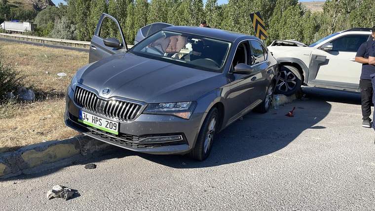 Yol kenarında gri otomobil ile beyaz otomobil çarpışmış; beyaz aracın ön kısmında hasar görülüyor.