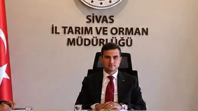 Sivas İl Tarım ve Orman Müdürlüğü'nde bir kişi oturuyor, arka planda tabela var.