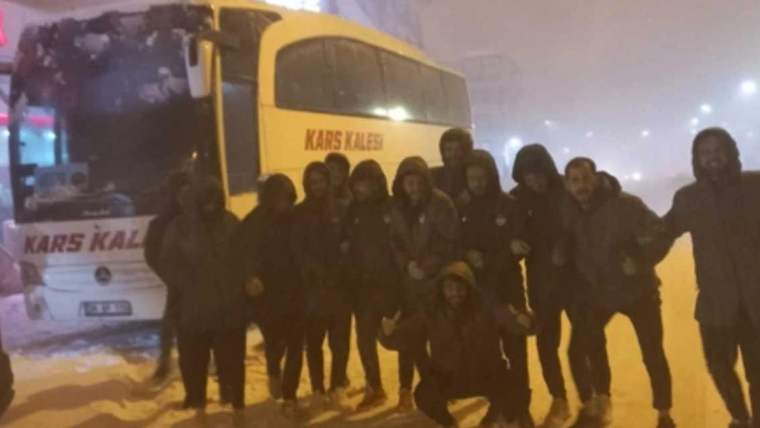 Kars 36 Spor'un oyuncuları, karla kaplı bir alanda otobüsün önünde duruyor.
