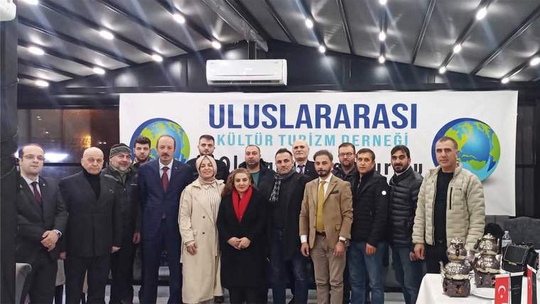 Üzerinde “Uluslararası Kültür ve Turizm Derneği” yazan pankartın önünde bir grup kişi yan yana duruyor.