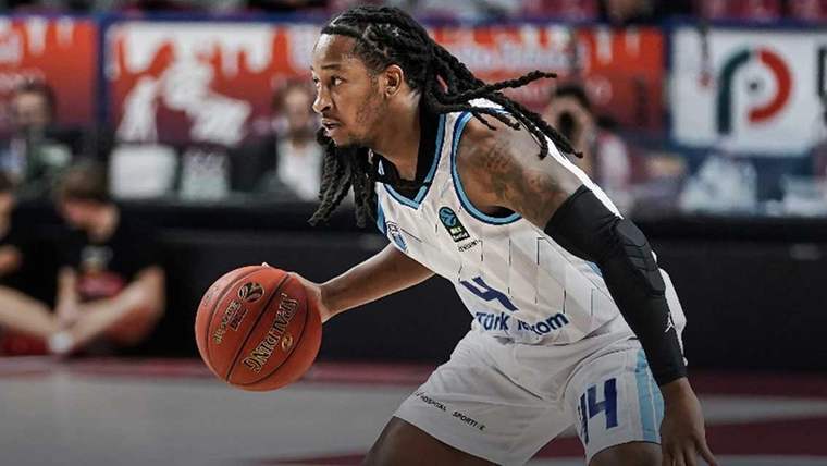 Türk Telekom forması giymiş bir basketbolcu, topu dribling yaparak ilerletiyor.