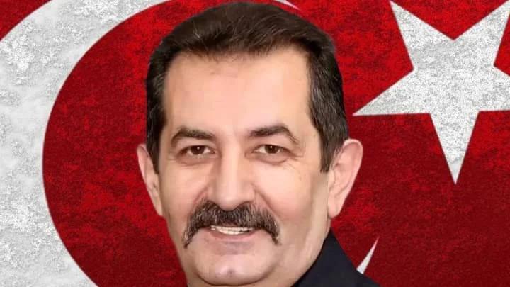 Bıyıklı bir erkek portresi, arka planda kırmızı Türk bayrağı ve beyaz ay yıldız motifiyle yer alıyor.