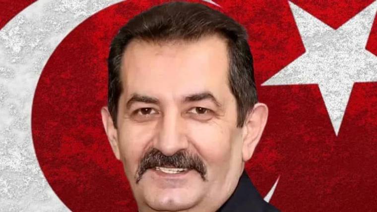 Bıyıklı bir erkek portresi, arka planda kırmızı Türk bayrağı ve beyaz ay yıldız motifiyle yer alıyor.