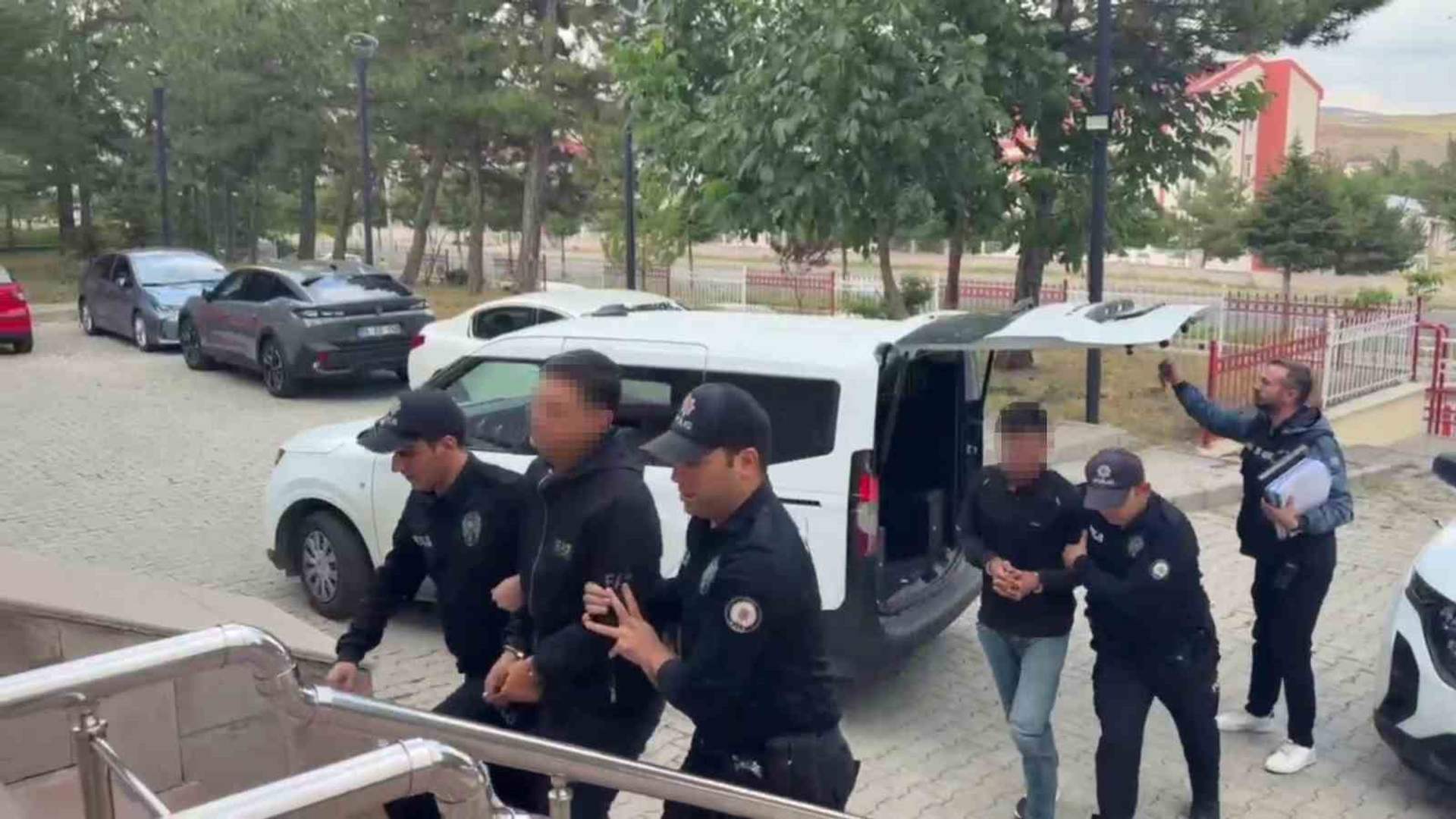 Polis üniformalı kişiler, yüzleri bulanıklaştırılmış bir kişiyi beyaz minibüsten çıkararak merdivenlere götürüyor.