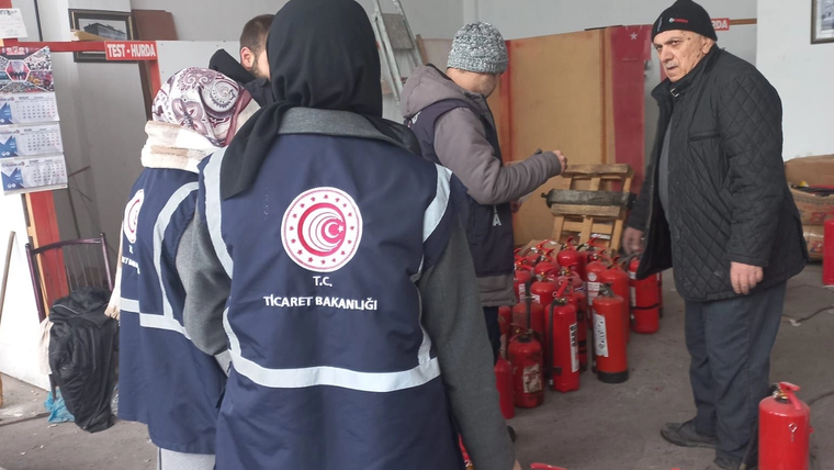 Yangın tüpü satan bir işletmede denetim yapan yetkililer, yangın tüplerinin bulunduğu alanda duruyor.