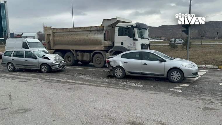 Yol kenarında hasar görmüş iki otomobil, park halindeki damperli kamyonun önünde duruyor.