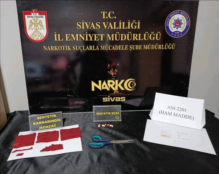 Sivas Valiliği ve İl Emniyet Müdürlüğü yazılı pano önünde paketler, makas ve "AM-2201 (HAM MADDE)" yazısı bulunuyor.