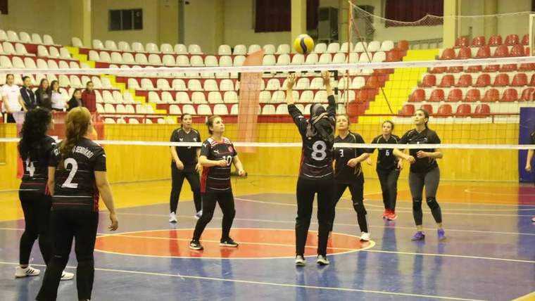 Voleybol sahasında, forma giymiş kadın sporcuların müsabaka sırasında pozisyon aldıkları bir an.