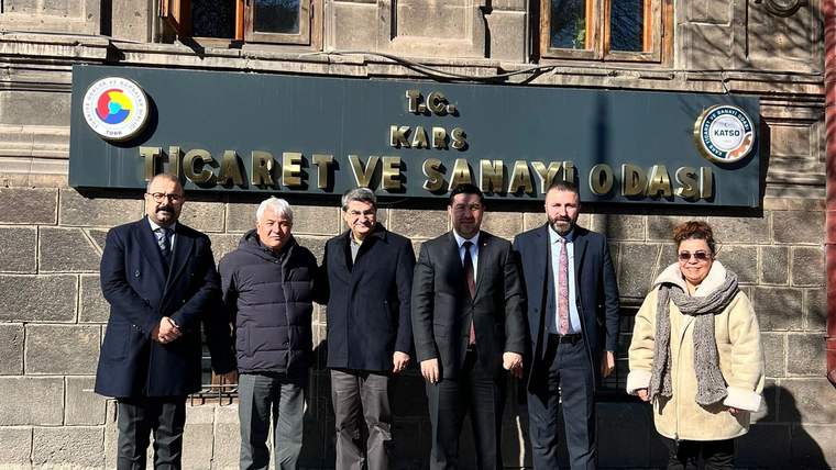 Kars Ticaret ve Sanayi Odası tabelası önünde altı kişi, taş binanın girişinde yan yana duruyor.
