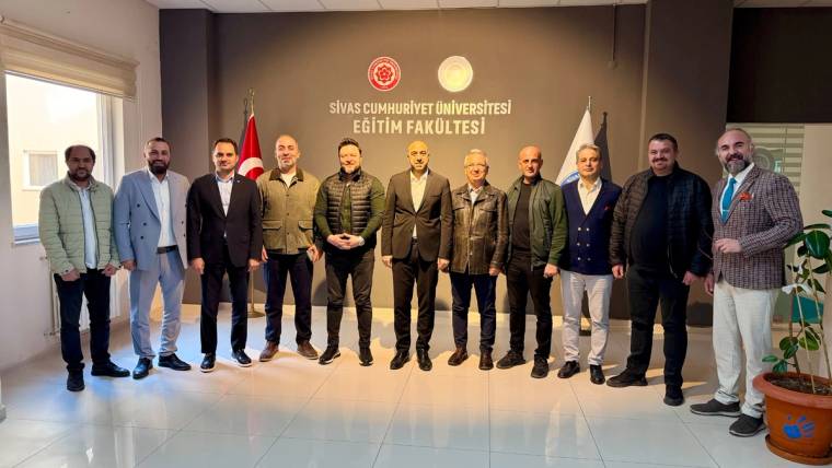 Sivas Cumhuriyet Üniversitesi Eğitim Fakültesi yazılı duvar önünde, yan yana duran 12 kişilik grup