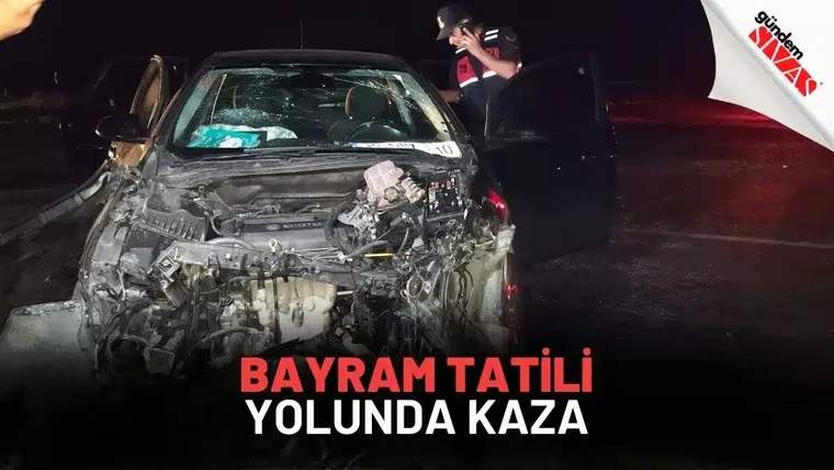 Gece çekiminde önü ağır hasarlı bir otomobilin yanında, açık kapı önünde duran bir kişi görülüyor.